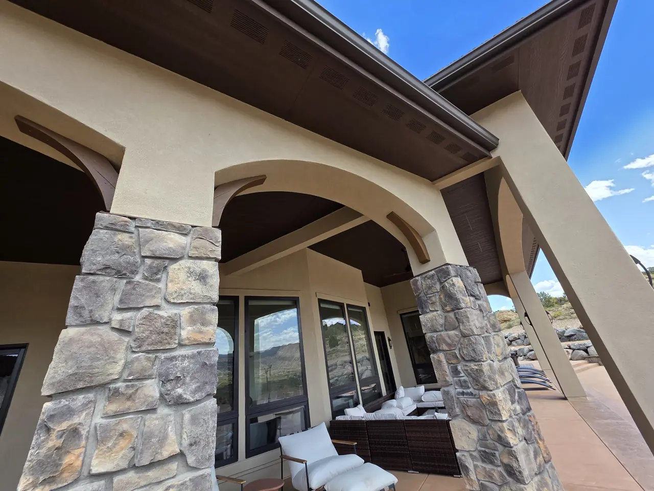 Covered porch arches with stained beams and stone columns
